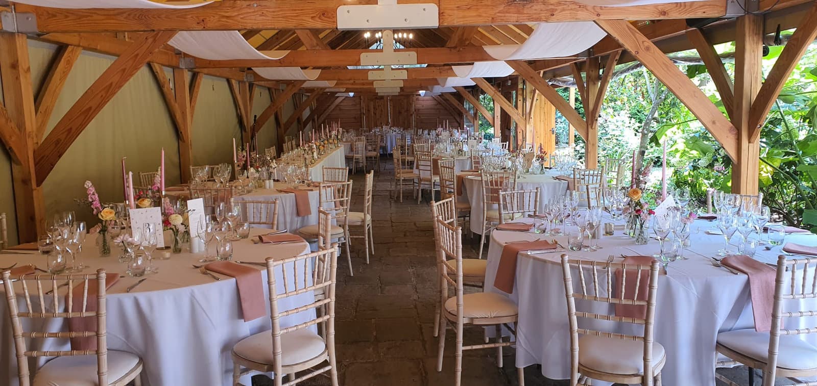 Wedding venue with round tables laid under a wooden roof