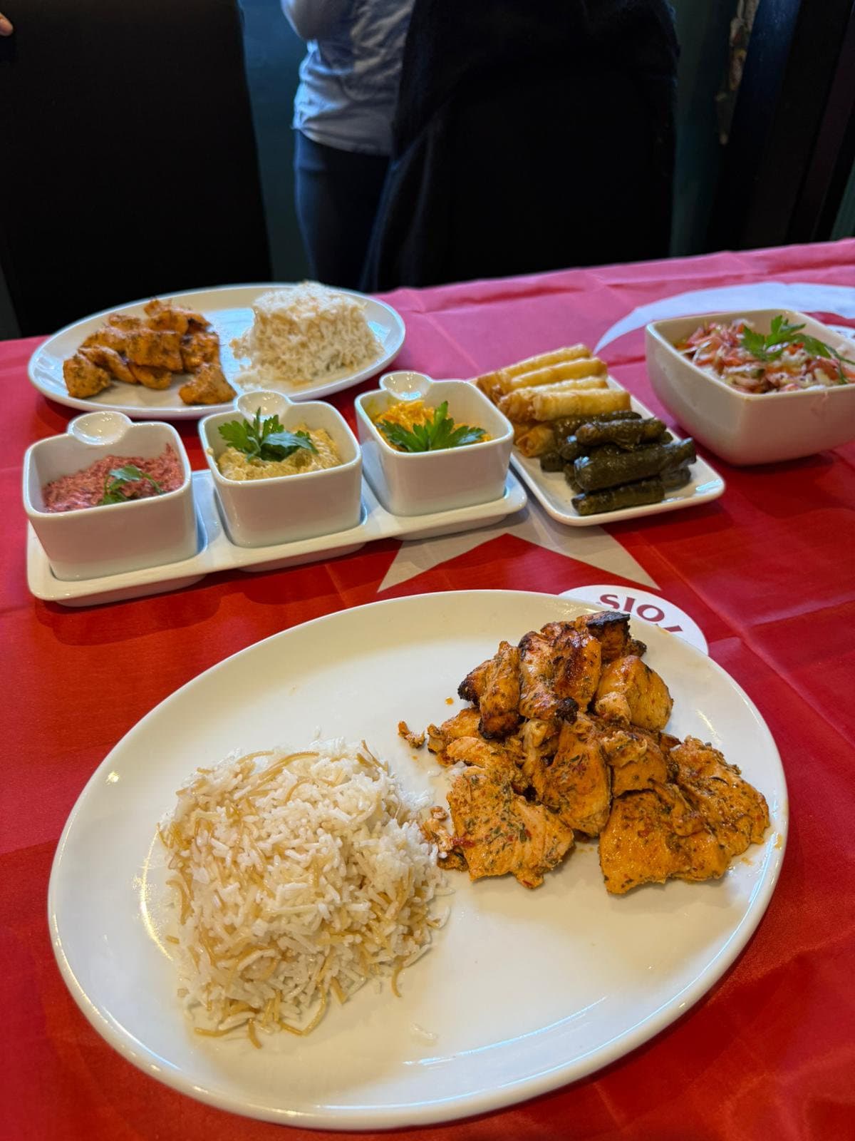 Turkish night spread of meze bowls, grilled chicken and rice on a red tablecloth