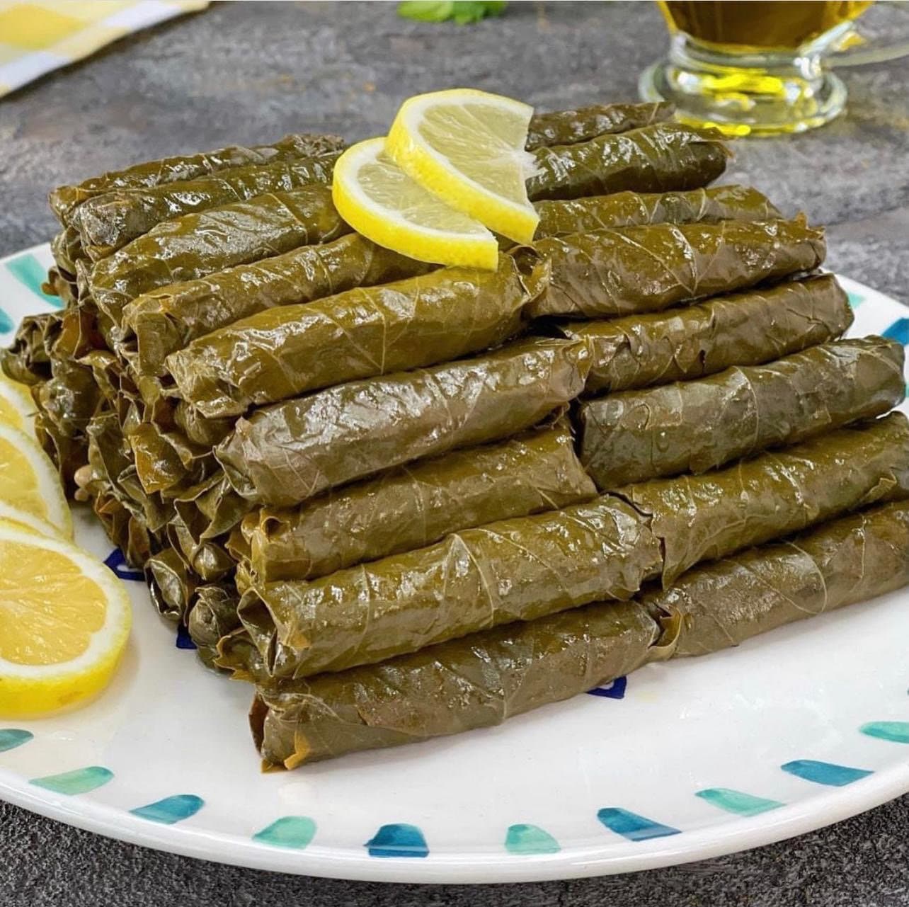Stuffed vine leaves stacked on a plate with lemon slices